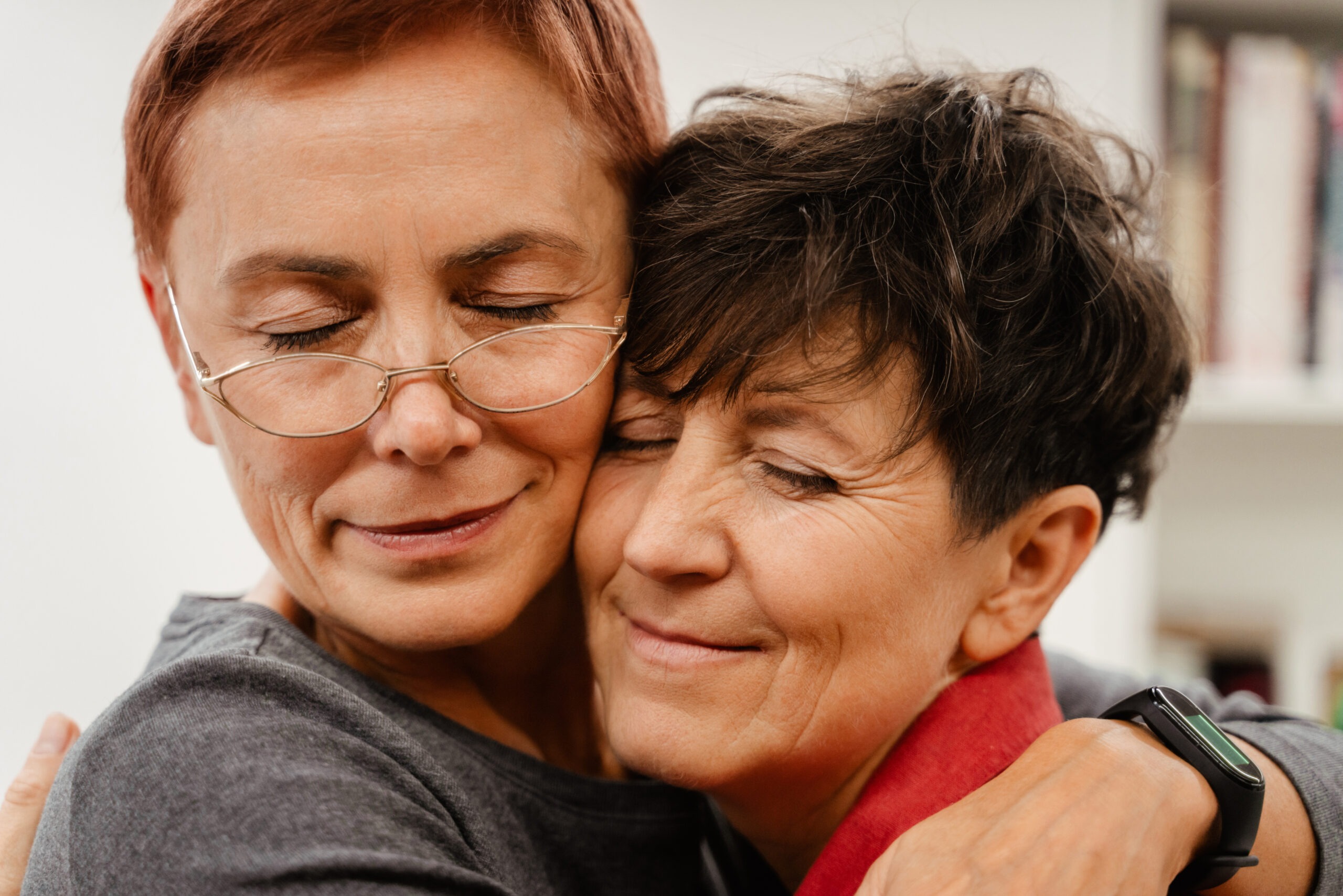 Mature lesbian couple hugging and smiling at home